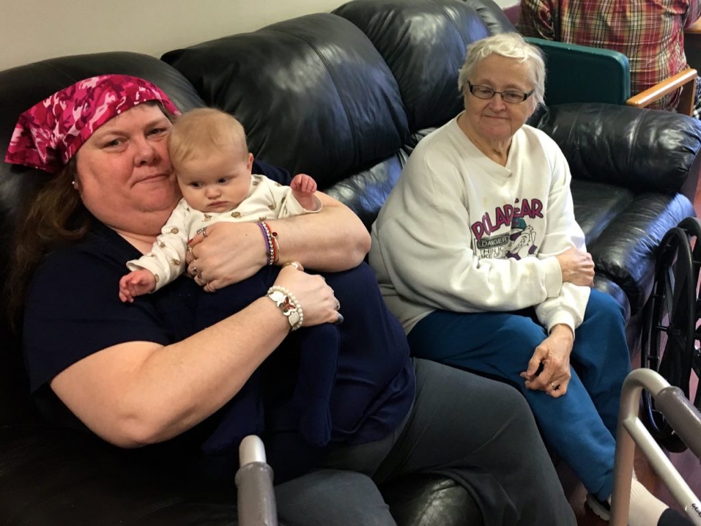 Jodilee holding Jeremiah while sitting by Hellen, the lady who was healed