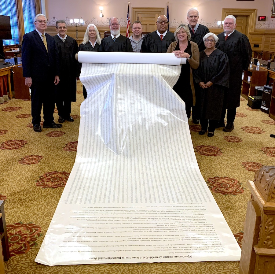 Justices pose with the unrolled Moral Outcry scroll 