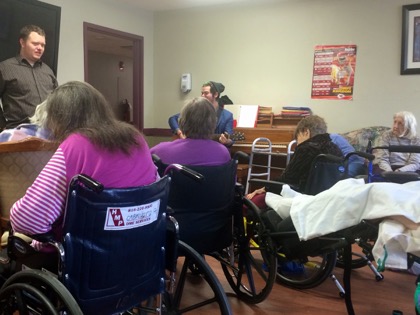 Jonathan helps lead seniors in prayer accompanied by an acoustic guitar